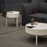 Modern round side tables in white with minimalistic design and contrasting black accents, set against a dark sofa.
