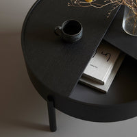 Black circular coffee table with a textured surface and minimalist design, showcasing subtle patterns and a modern look.