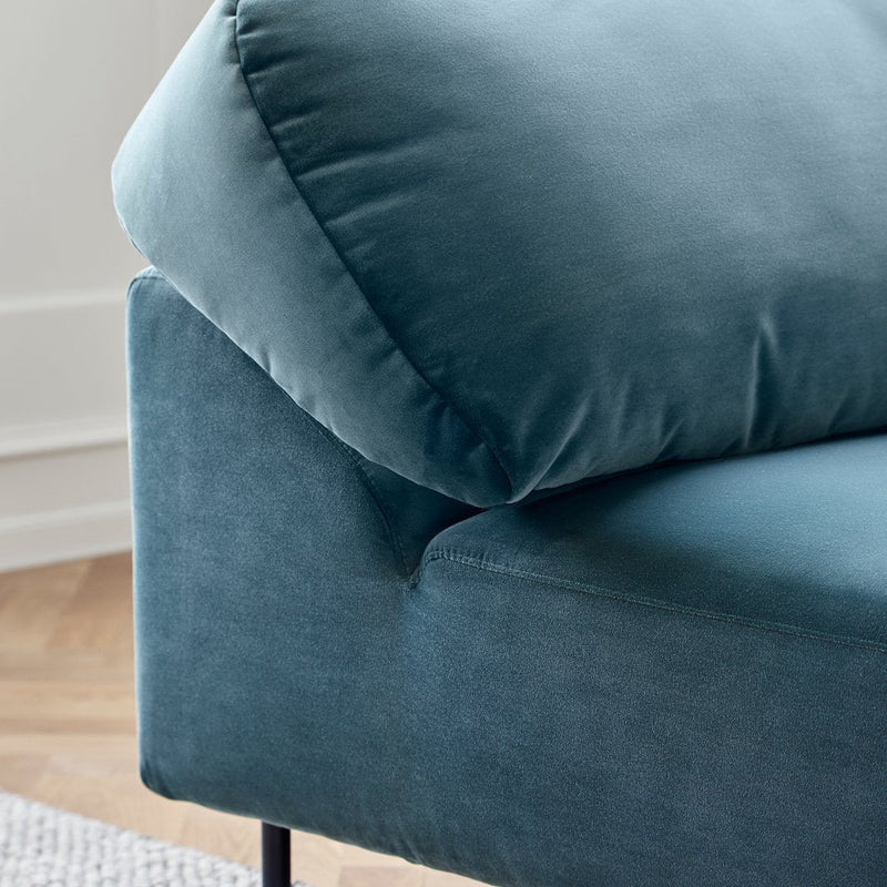"Soft teal velvet sofa with a plush cushion, featuring clean lines and a modern design."