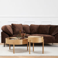 Brown suede sectional sofa with natural wooden accent tables on a soft white rug. Modern, cozy, and inviting decor.