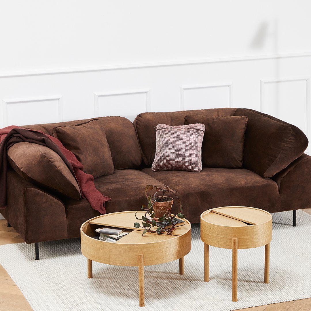 Brown velvet sofa with a textured finish, paired with round wooden coffee tables and a cozy maroon throw.
