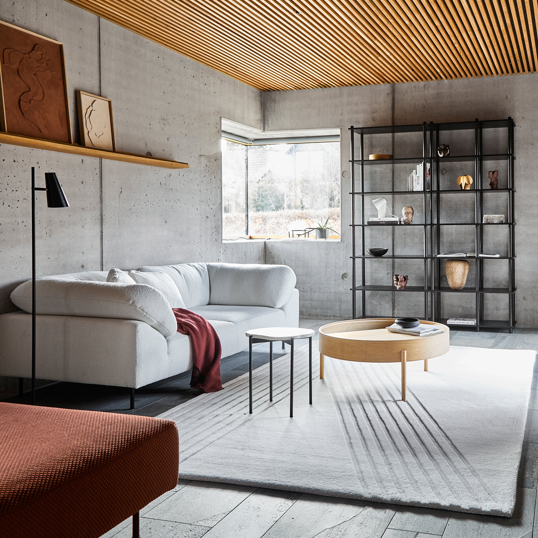 Modern living room featuring a neutral palette with gray, white, and warm wood tones, accented by deep red hues and soft textures.