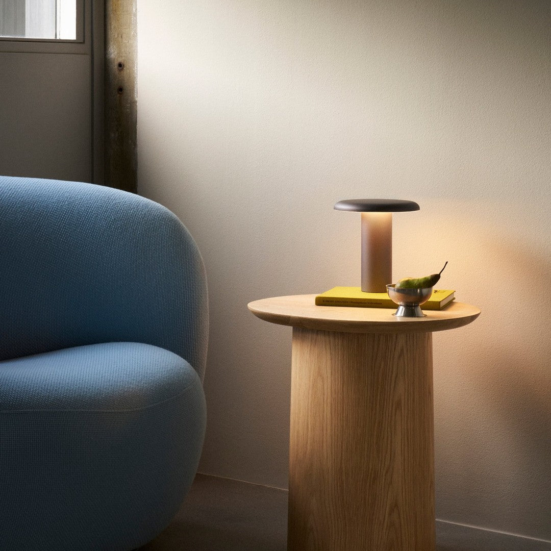 Soft blue couch, natural wood table, yellow accents, and warm lighting create a modern, cozy atmosphere.