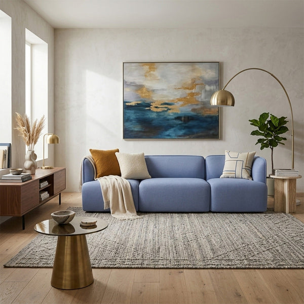 Light blue sofa with neutral throw pillows, gray patterned rug, and warm wooden accents in a modern living room.