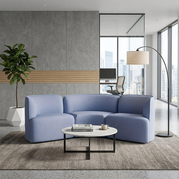 Light blue curved sofa in a modern setting, paired with a white marble table and neutral-toned rug.