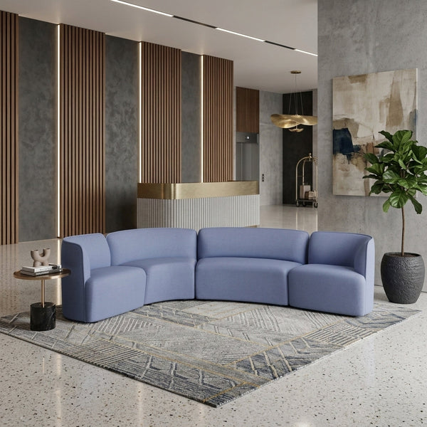Curved blue sofa with a minimalist design, paired with a geometric patterned rug in neutral tones.
