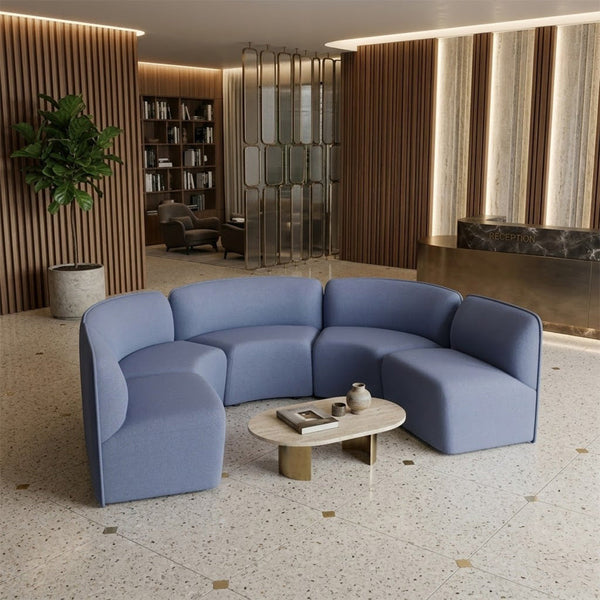 Curved sectional sofa in soft blue fabric, featuring minimalistic design and seamless upholstery for a modern look.