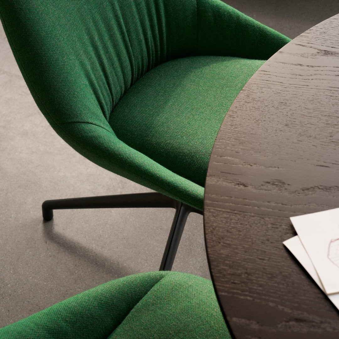 Green fabric chair close-up with a textured pattern, paired with a sleek dark wood round table.