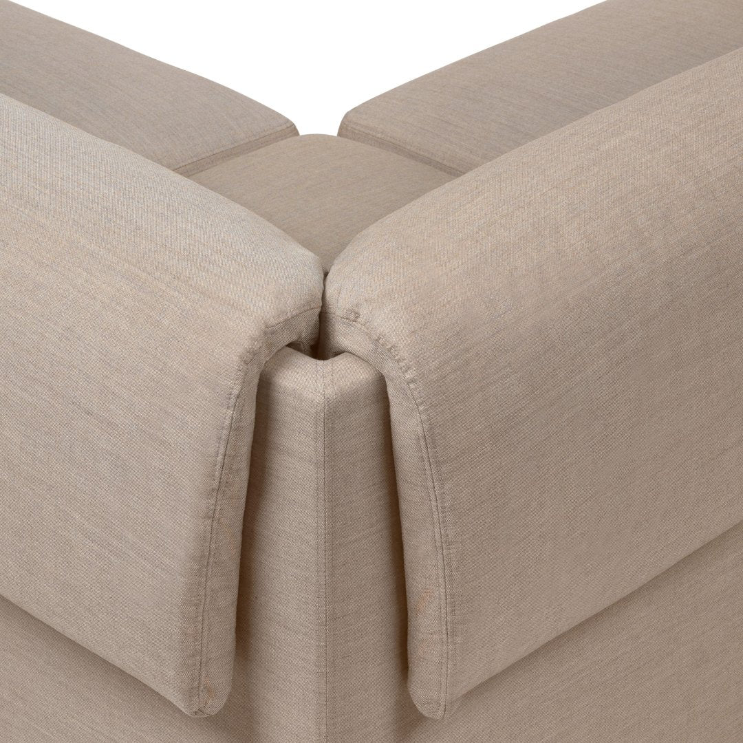Beige textured fabric corners on a modern, minimalistic couch with subtle stitching details.