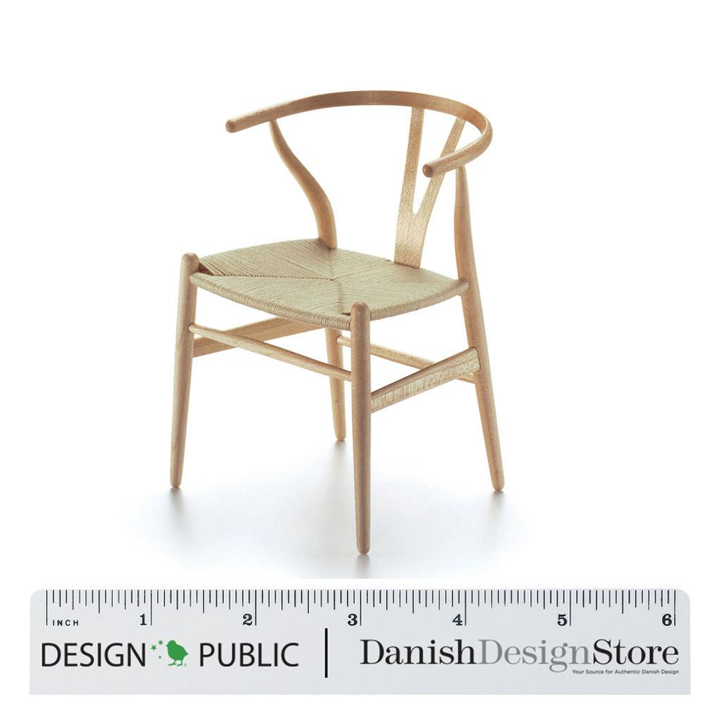 Natural wood chair with a minimalist design and woven seat, featuring smooth lines and a light finish.