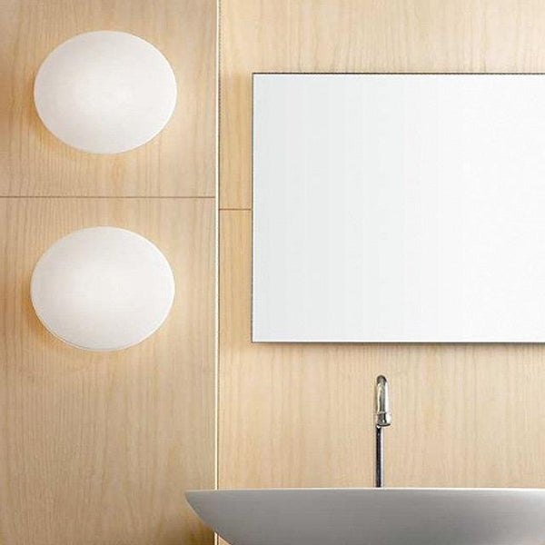 Round white wall sconces paired with a minimalist rectangular mirror against natural wood paneling. Modern and clean design.