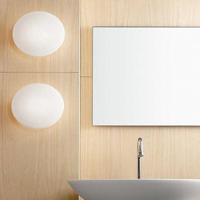 Round white wall sconces paired with a minimalist rectangular mirror against natural wood paneling. Modern and clean design.