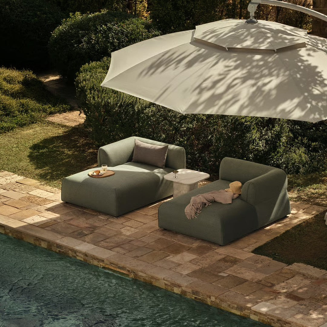 Modern outdoor lounge chairs in soft gray upholstery with clean lines, complemented by a large beige umbrella.