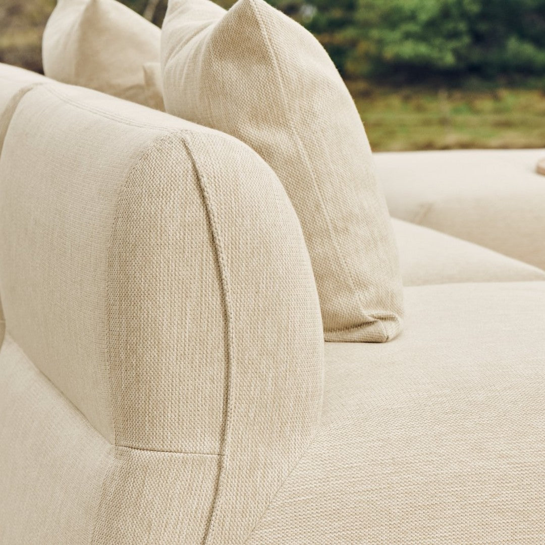Beige upholstered sofa with textured fabric and plush pillows, showcasing a subtle, elegant pattern.