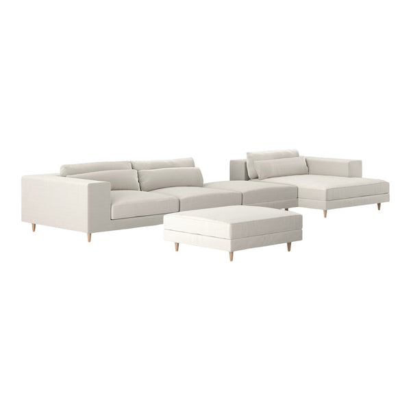 Modern light gray sectional sofa with plush cushions and wooden legs, complemented by a matching ottoman.