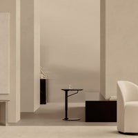 Minimalist room with soft beige walls, sleek black furniture, and a white accent chair. Elegant, neutral color palette.