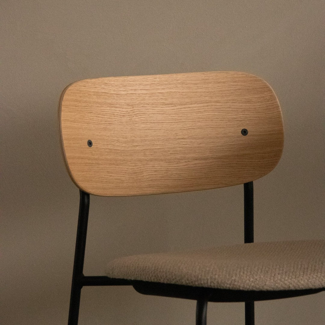 Natural wood finish backrest with black metal frame and textured beige upholstery seat. Simple, modern design.