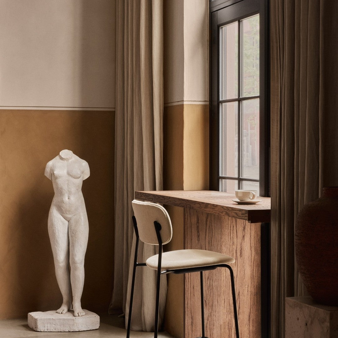 Statue in white, beige walls, brown accents, and soft fabric curtains create a serene, elegant interior scene.