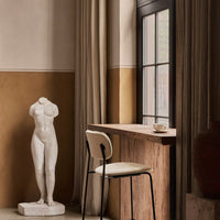Statue in white, beige walls, brown accents, and soft fabric curtains create a serene, elegant interior scene.