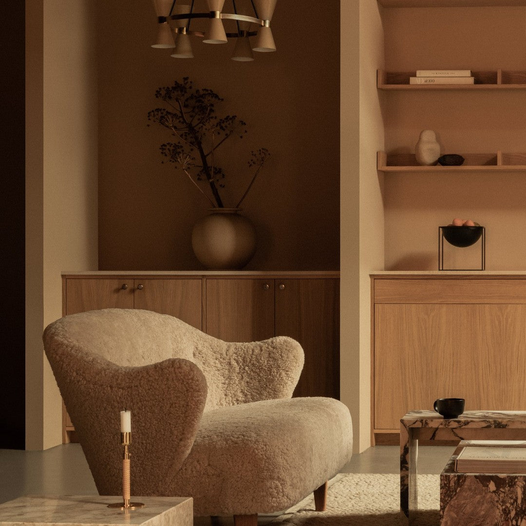 Soft beige armchair with textured fabric, complemented by earthy tones and subtle patterns in a minimalist interior setting.