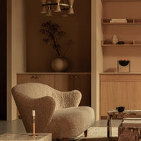 Soft beige armchair with textured fabric, complemented by earthy tones and subtle patterns in a minimalist interior setting.