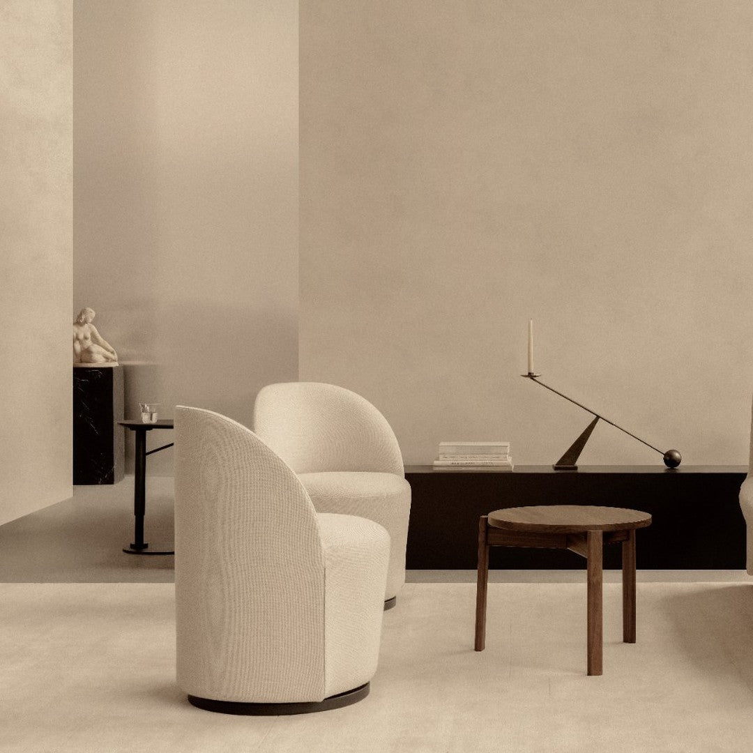 Cream curved chairs with soft texture, set against a minimalistic beige backdrop and dark furniture accents.