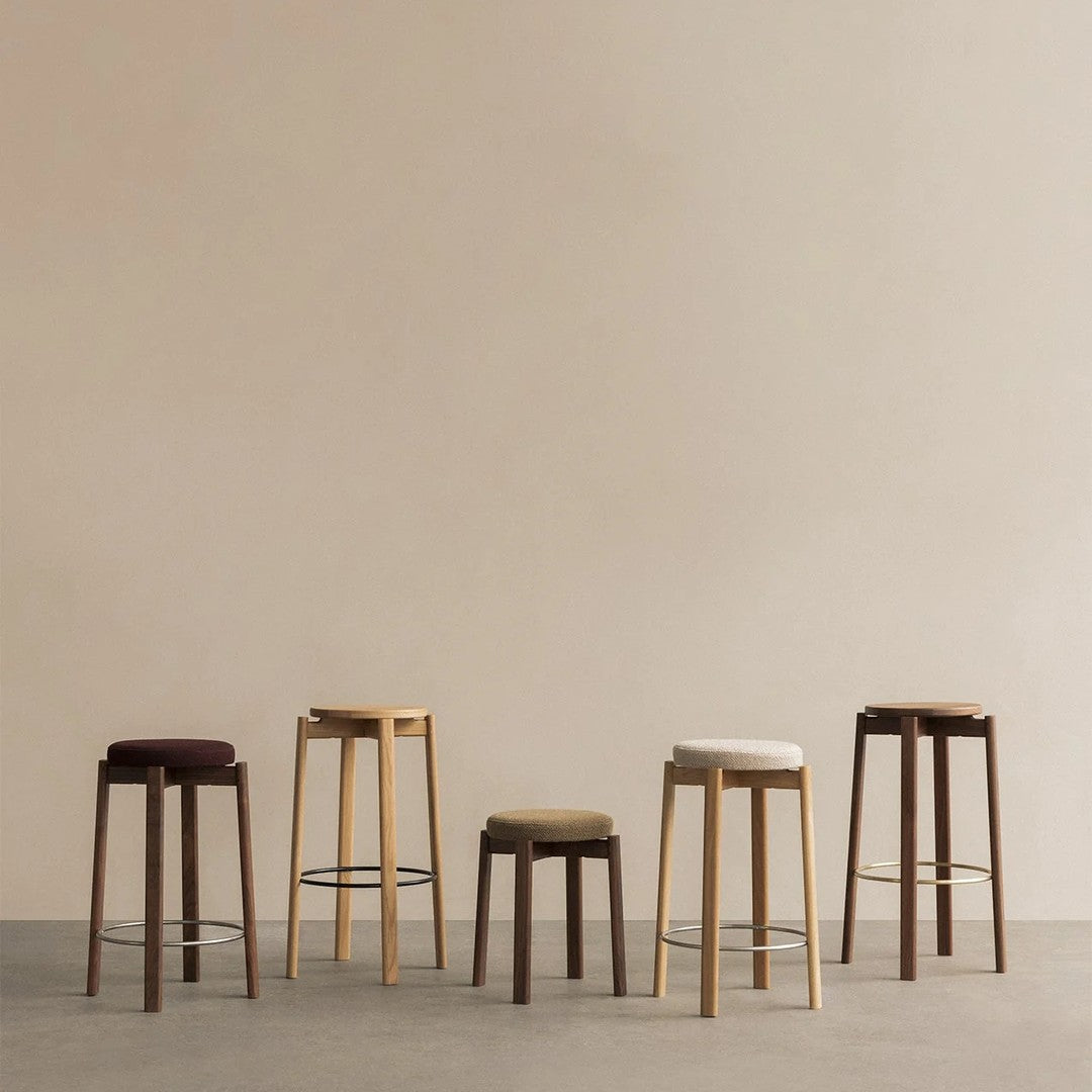 Collection of five stylish bar stools in muted colors: dark brown, light beige, olive green, and creamy white.