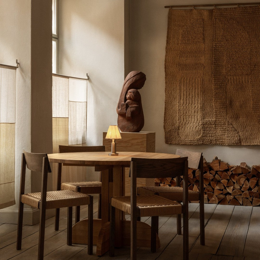 Wooden dining table and chairs in warm tones, with earthy textures and subtle patterns against a cozy backdrop.