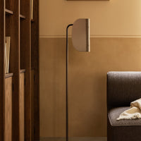 Sleek floor lamp in soft beige and brown tones, featuring a minimalist design with curved lines and a warm ambiance.