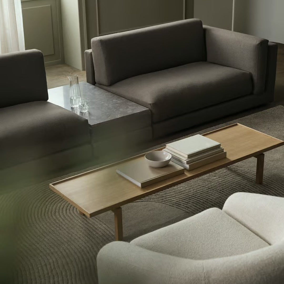 Modern living room featuring neutral gray sofas and an elegant wooden coffee table on a textured rug.