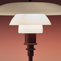 Stylish white lampshade with a layered design, complemented by a sleek brown base against a warm gradient background.