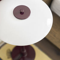 White glass lamp shade with a maroon knob, featuring a sleek, modern design and smooth, glossy finish.