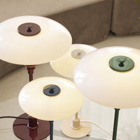 Multi-colored lamps with glossy white shades, featuring burgundy, green, and navy accents. Contemporary design elements.