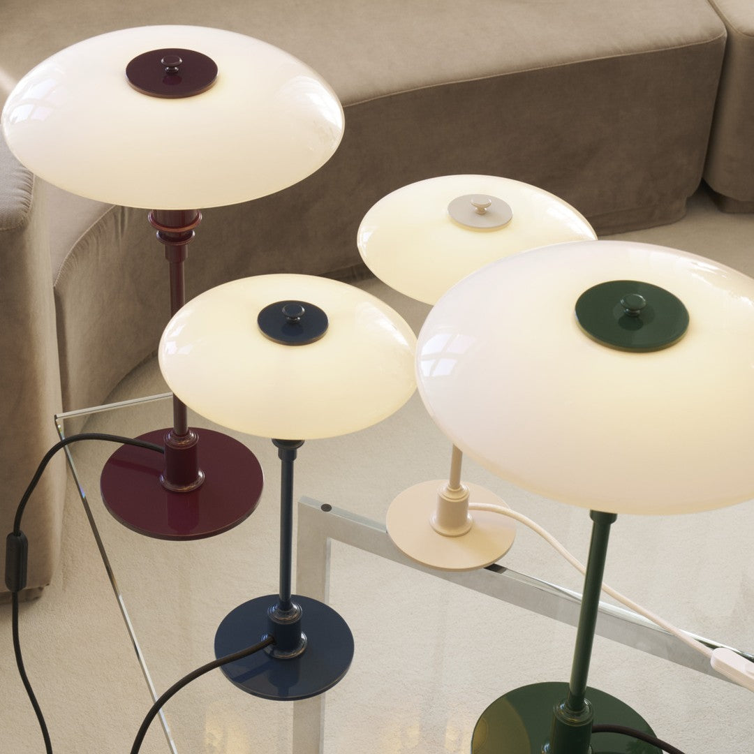 "Stylish table lamps in cream, deep green, burgundy, and navy with sleek circular shades and modern bases."