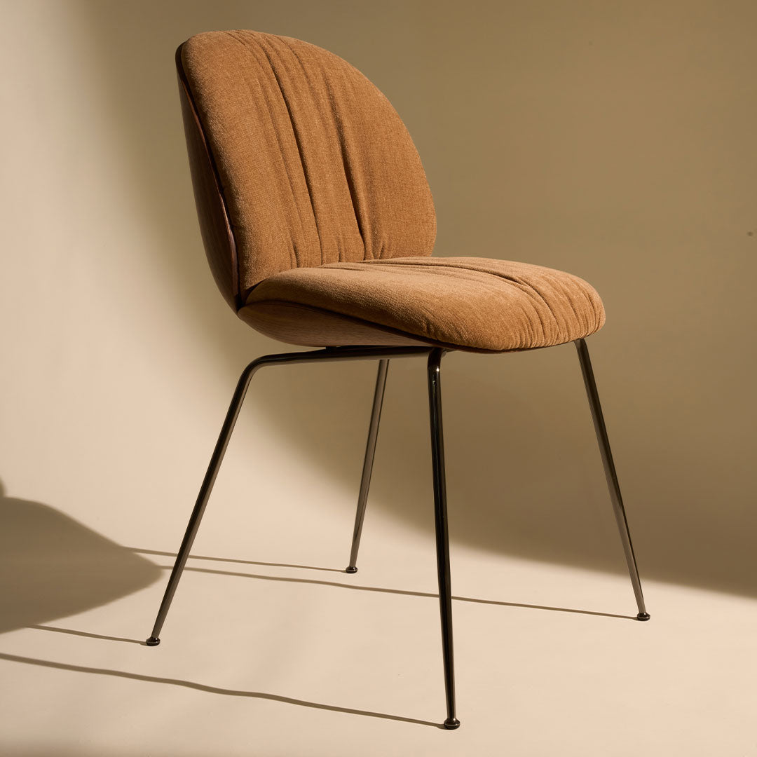 Brown upholstered chair with vertical ribbed pattern and sleek black metal legs, set against a neutral background.