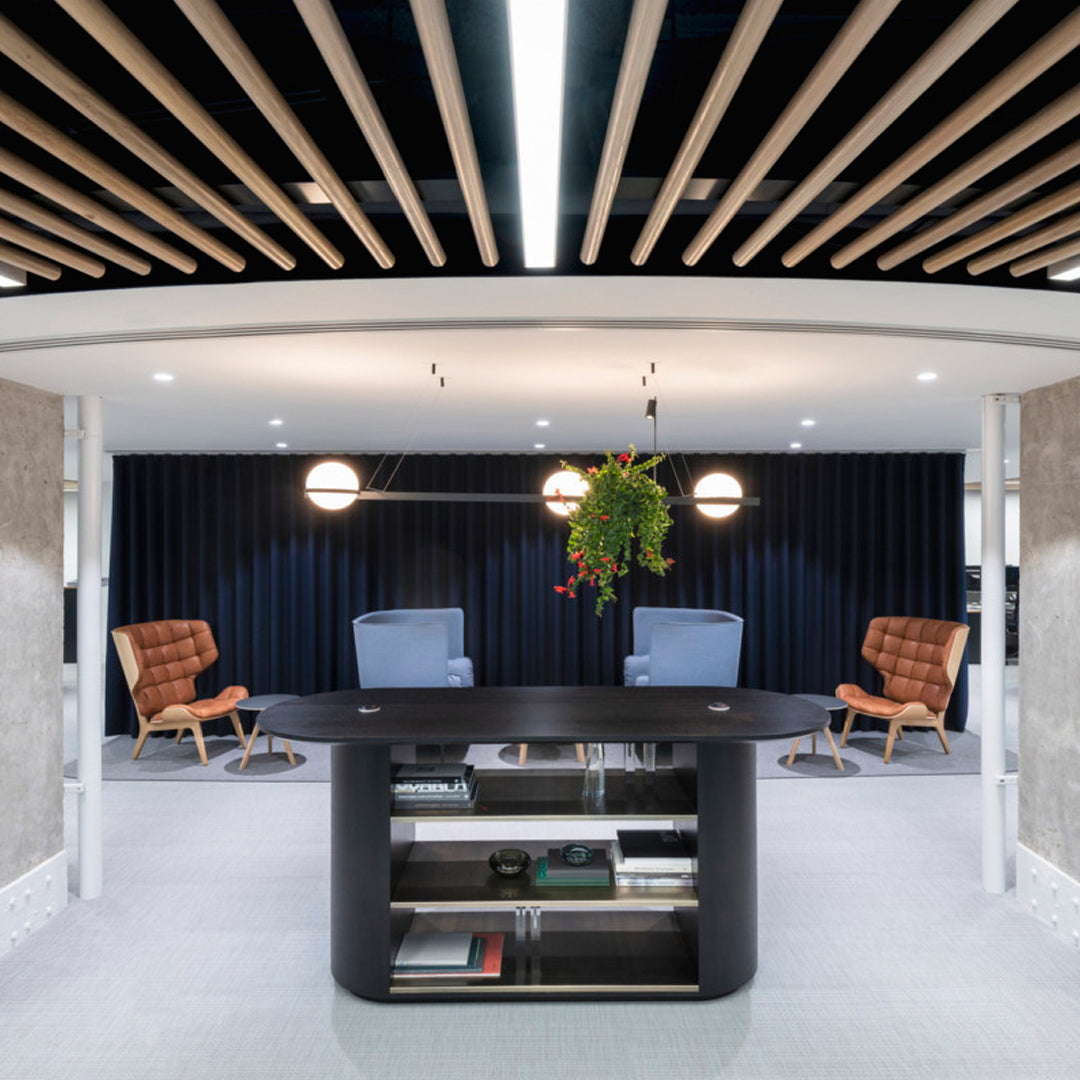 Modern reception area featuring warm wood tones, sleek black surfaces, and a dark blue accent wall.