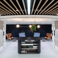 Modern reception area featuring warm wood tones, sleek black surfaces, and a dark blue accent wall.