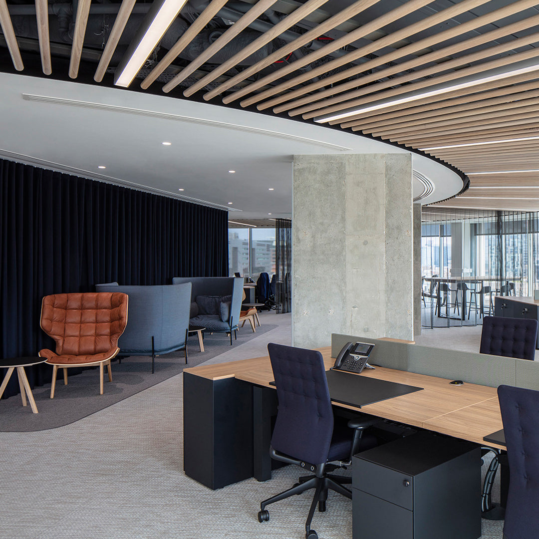 Modern office with wooden accents, gray and black furniture, and a patterned carpet, featuring cozy seating areas.