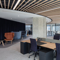Modern office with wooden accents, gray and black furniture, and a patterned carpet, featuring cozy seating areas.