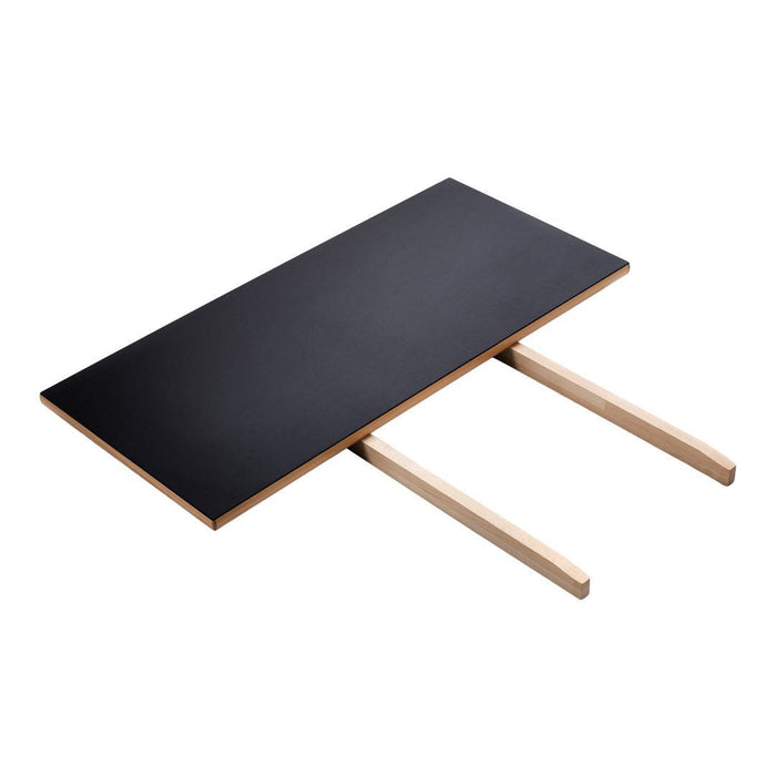 Black rectangular tabletop with natural wood legs, featuring a sleek, minimalist design. Perfect for modern decor.