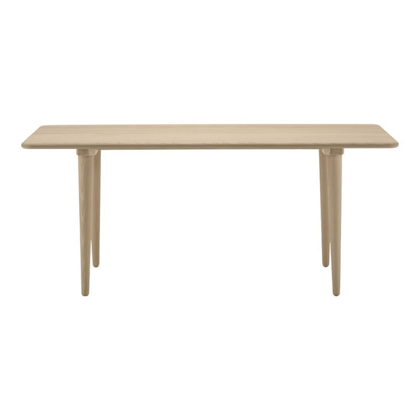 Beige rectangular table with smooth surface and tapered legs, showcasing a minimalist design and neutral color palette.