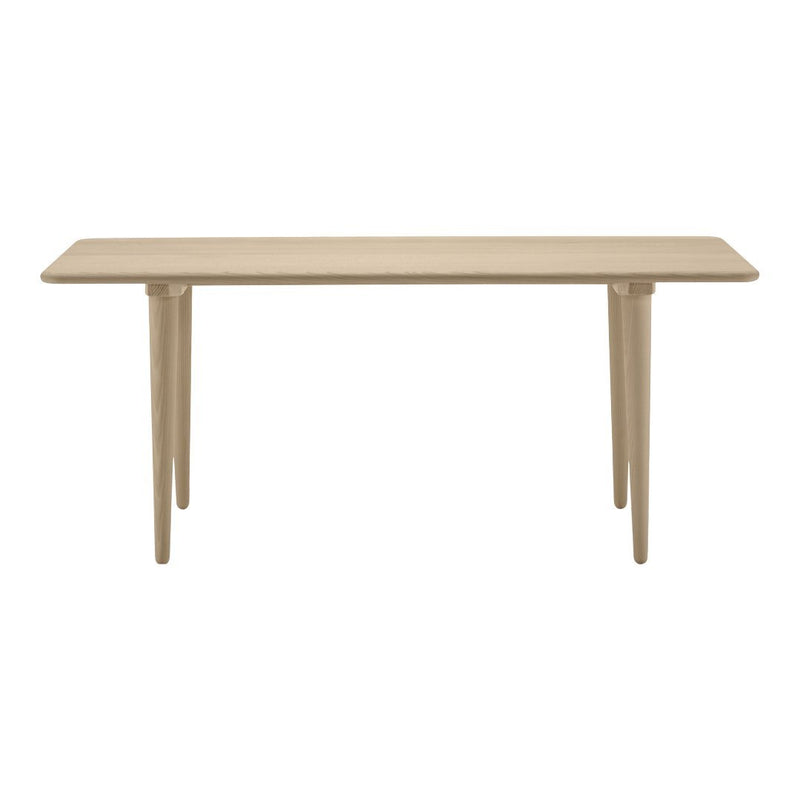 Beige rectangular table with smooth surface and tapered legs, showcasing a minimalist design and neutral color palette.