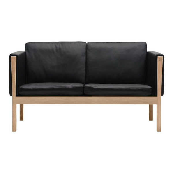 Black leather two-seater sofa with a natural wood frame, featuring a sleek, minimalist design.