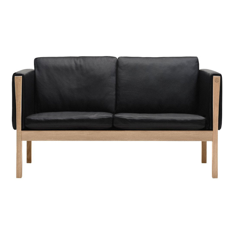 Black leather two-seater sofa with a natural wood frame, featuring a sleek, minimalist design.
