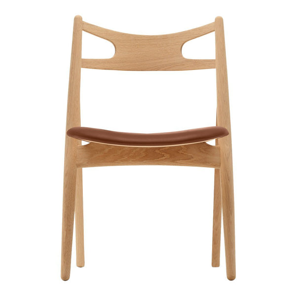 Natural wood chair with a light oak finish and a rich brown leather seat, featuring a minimalist design.