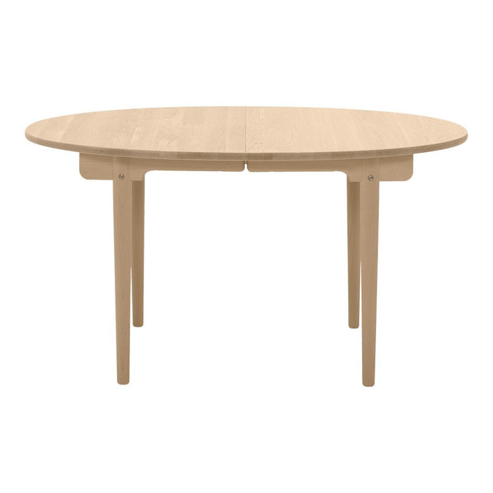 Light natural wood oval dining table with smooth finish and minimalist design, perfect for modern interiors.