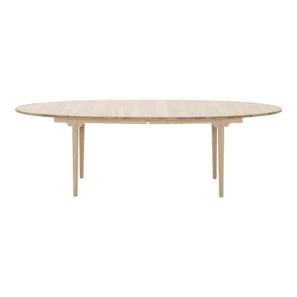 Light wood oval dining table with a smooth finish and minimalist design, showcasing natural wood grain patterns.