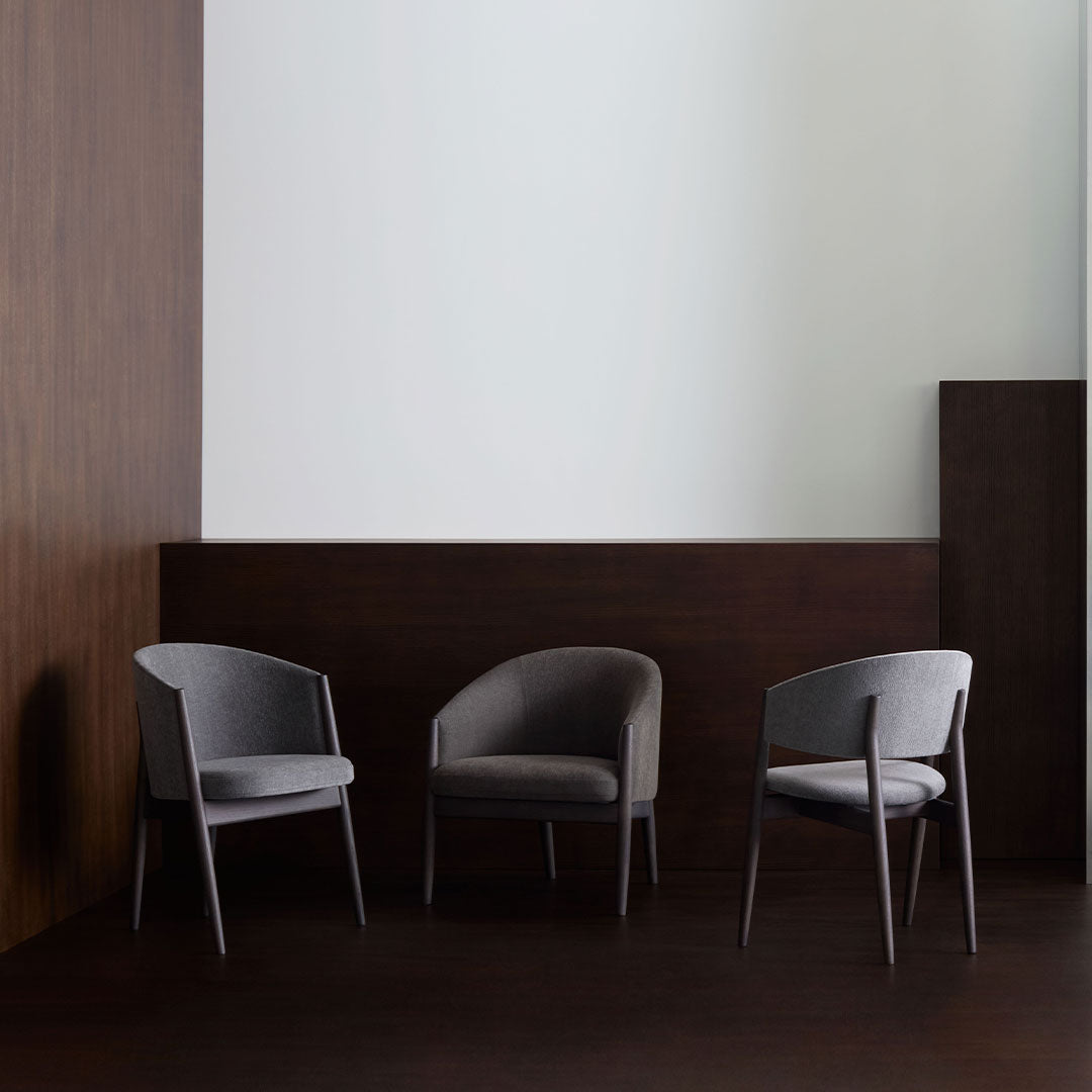 Gray upholstered chairs against a dark wood backdrop, creating a modern and minimalist look.