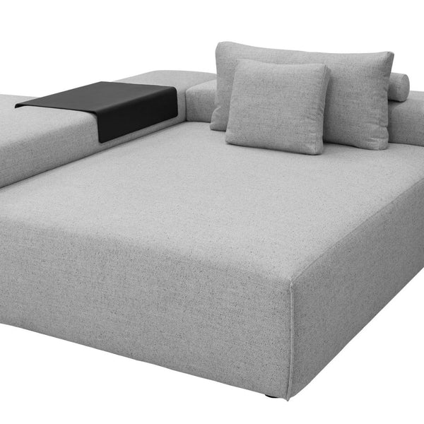 Modern gray sofa with sleek lines, featuring light gray fabric and a contrasting black side table. Minimalist design.