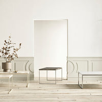 "Stylish minimalist coffee tables in white and black, set against a soft gray wall with natural wood flooring."